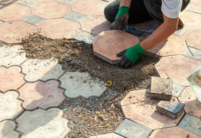 A person laying pavers down in the dirt